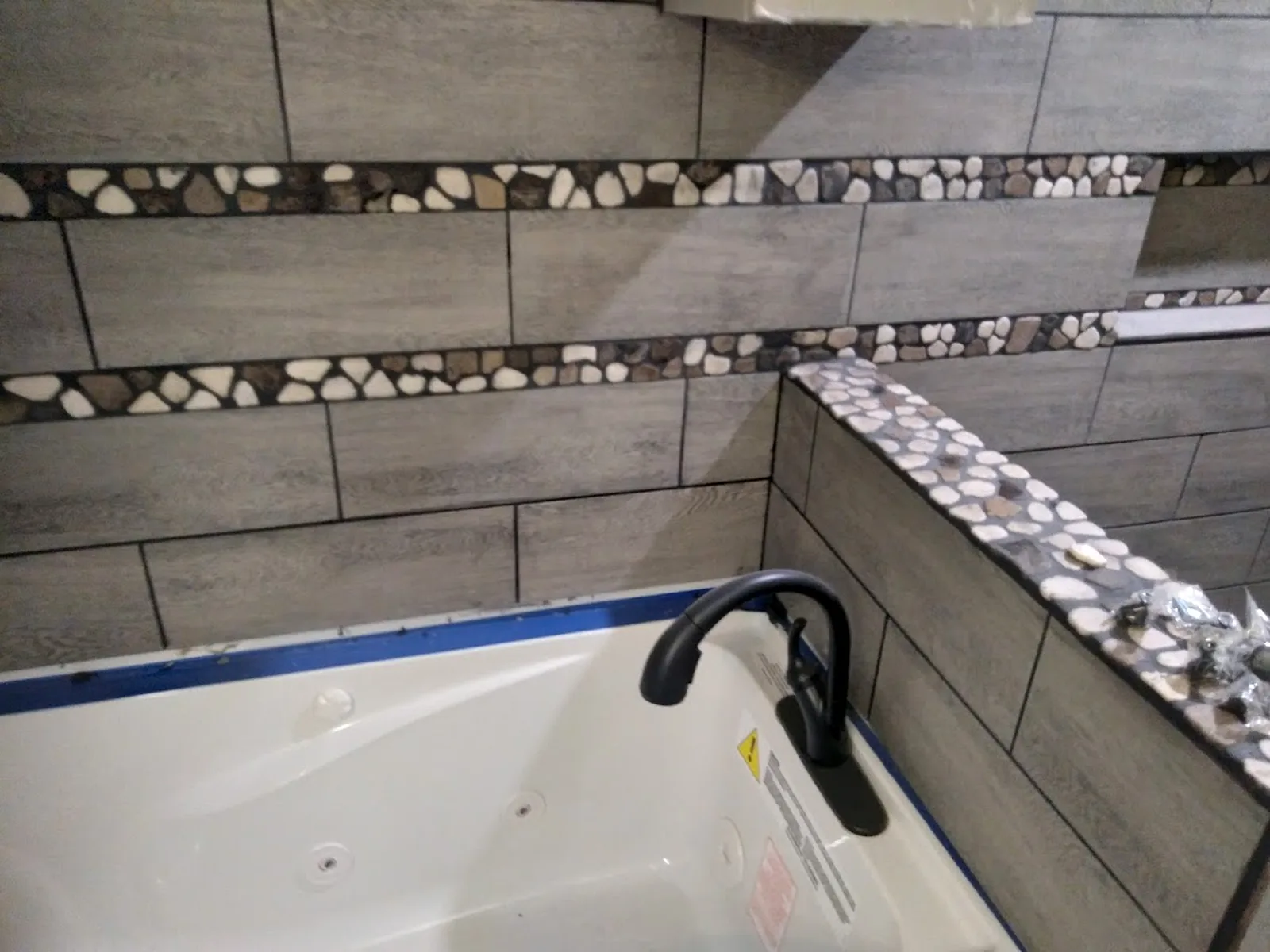 Finished bathroom tile wall with stone accent band