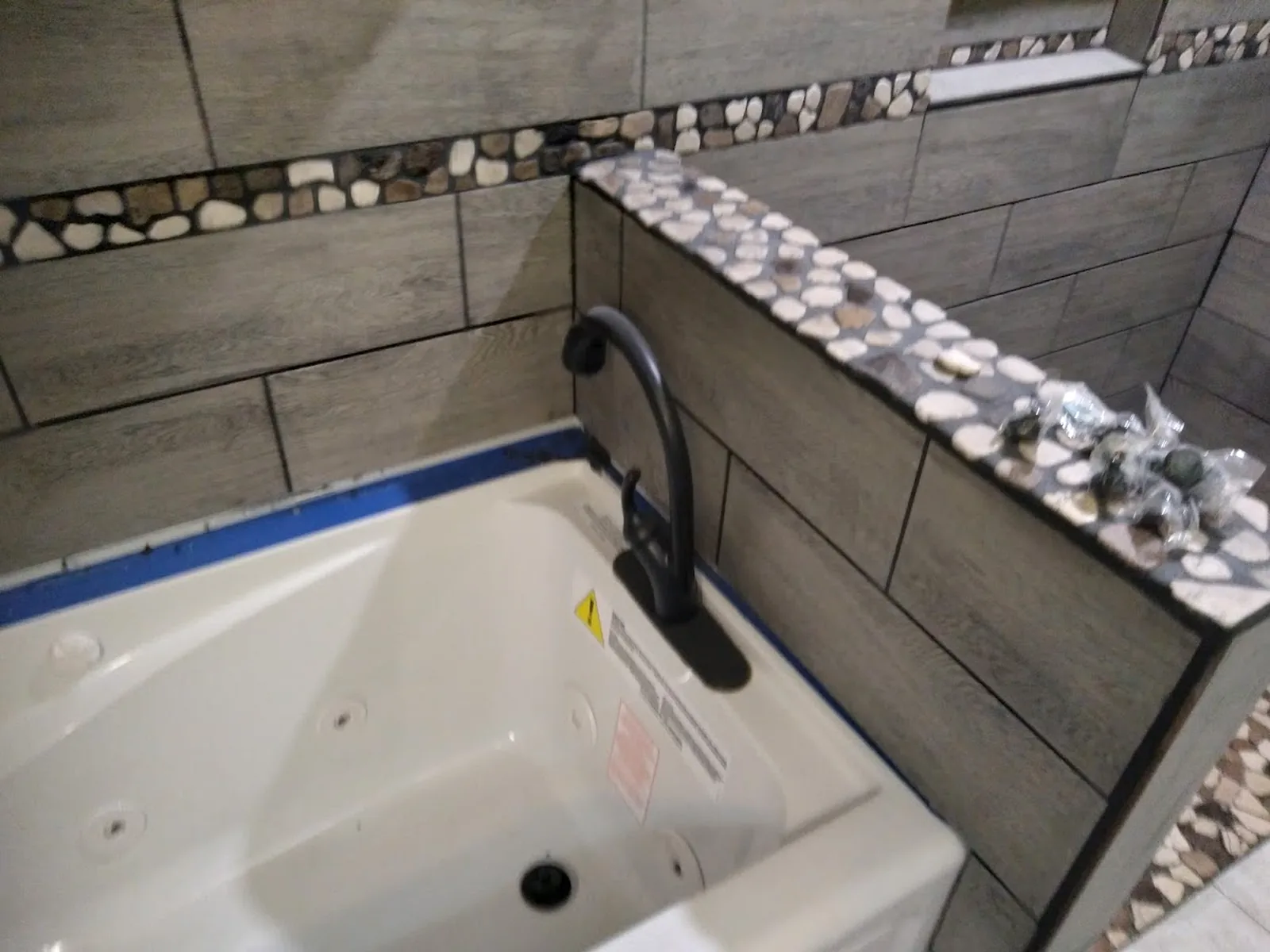 Finished bathroom tub surround with tile and stone accent detail